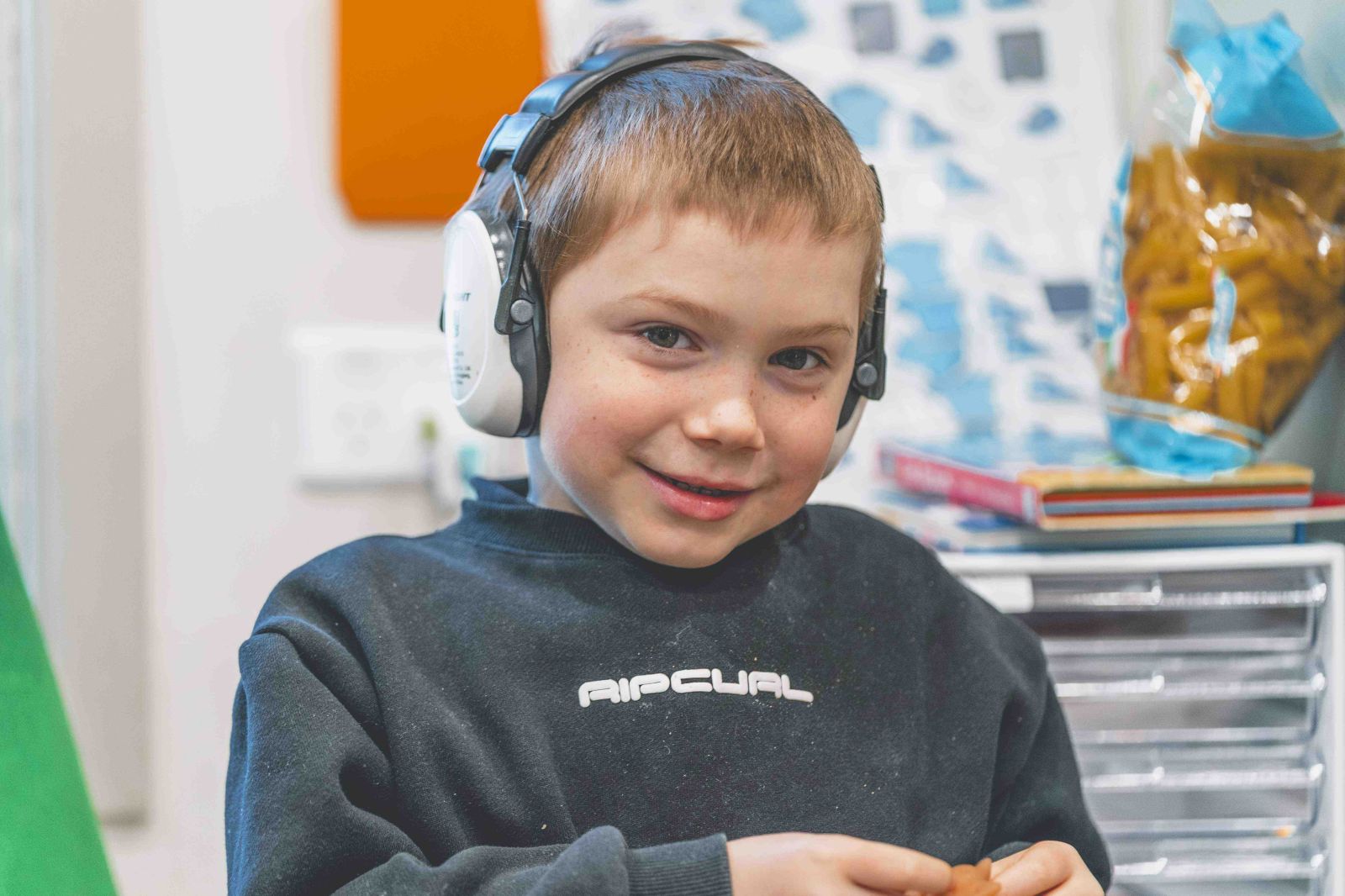 Student wearing headphones smiles during classroom activity